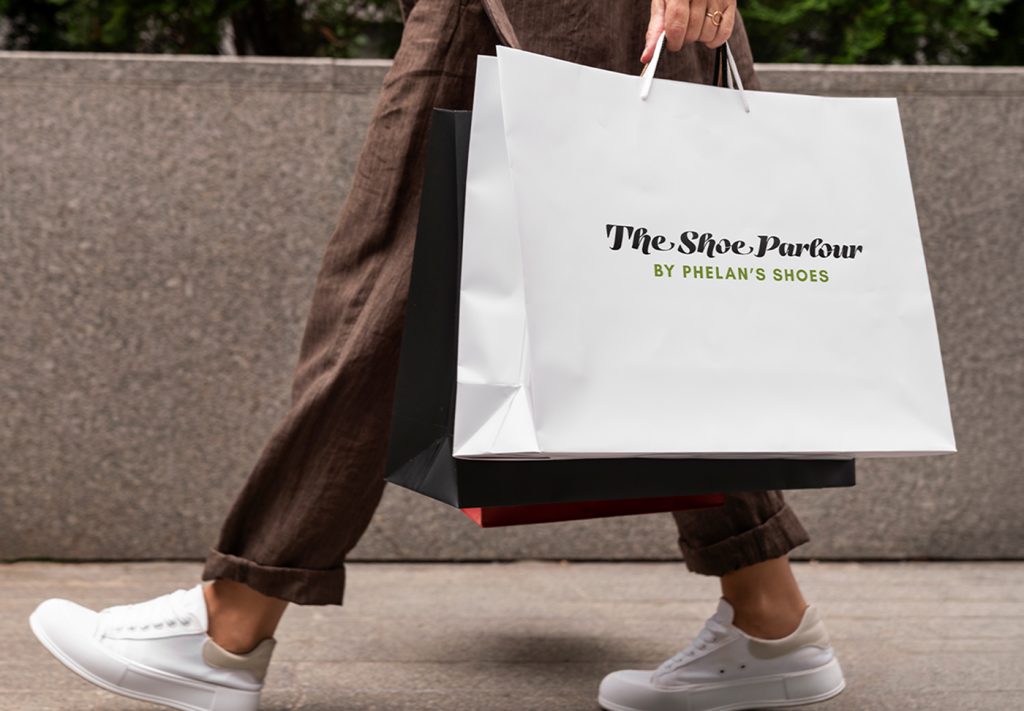 Woman carrying a The Shoe Parlour by Phelan's Shoes branded shopping bag